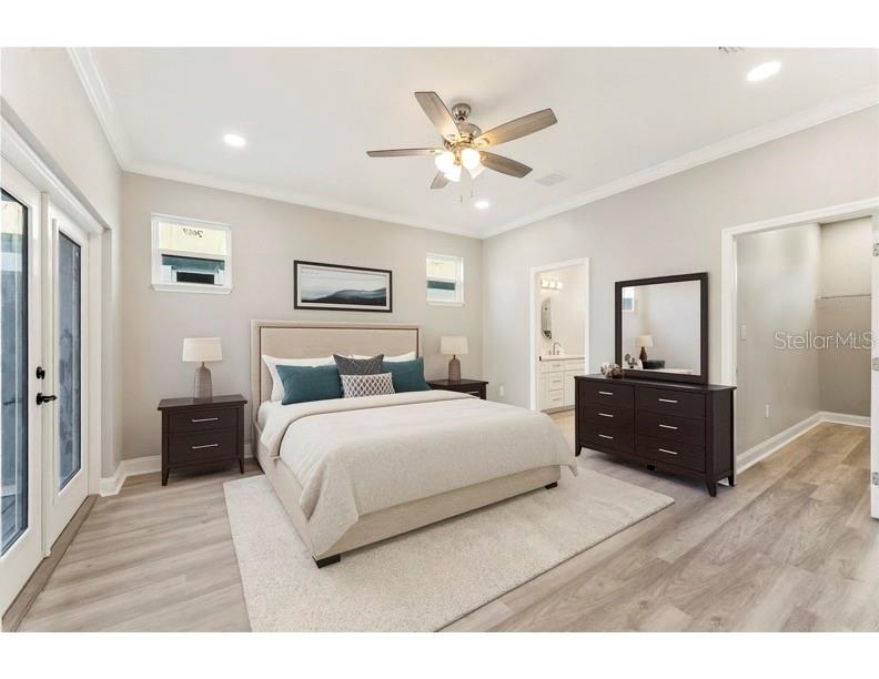 A bedroom with light wood floors, a beige bed, dark furniture, and a ceiling fan — 809 W LINEBAUGH AVENUE UNIT 1B, TAMPA, FL