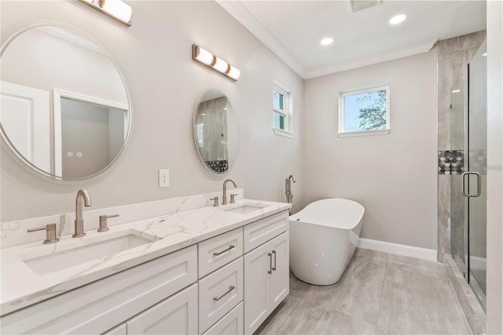 A modern bathroom features a double vanity with marble countertops, a soaking tub, and shower — 809 W LINEBAUGH AVENUE UNIT 1B, TAMPA, FL