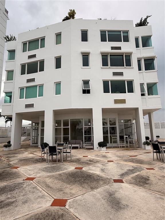 A multi-story white building with a paved patio area and outdoor seating — 5245 ISLA VERDE AVENUE UNIT 208, CAROLINA, PR
