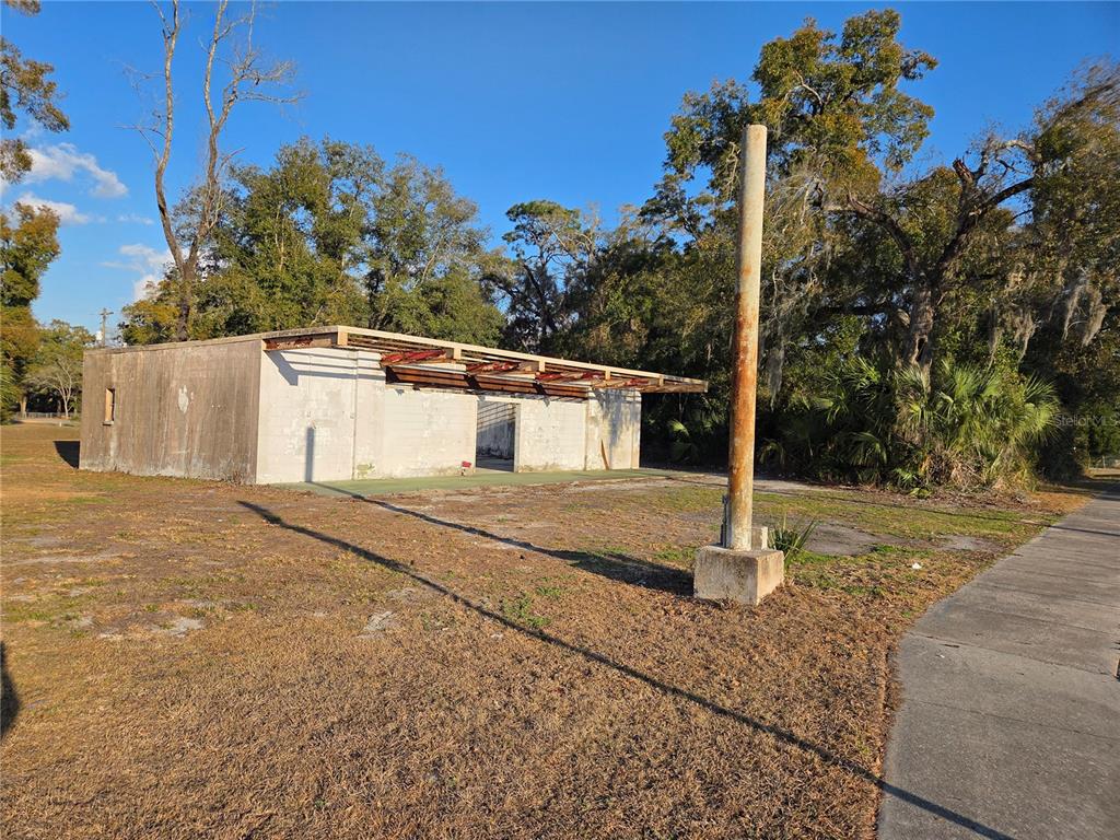 An exterior view of a weathered, single-story concrete block structure with an open-sided roof — 715 N YOUNG BOULEVARD, CHIEFLAND, FL