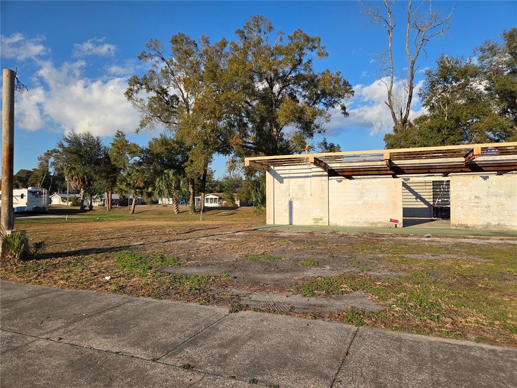 An exterior view shows a vacant lot with a concrete structure and a metal roof frame — 715 N YOUNG BOULEVARD, CHIEFLAND, FL