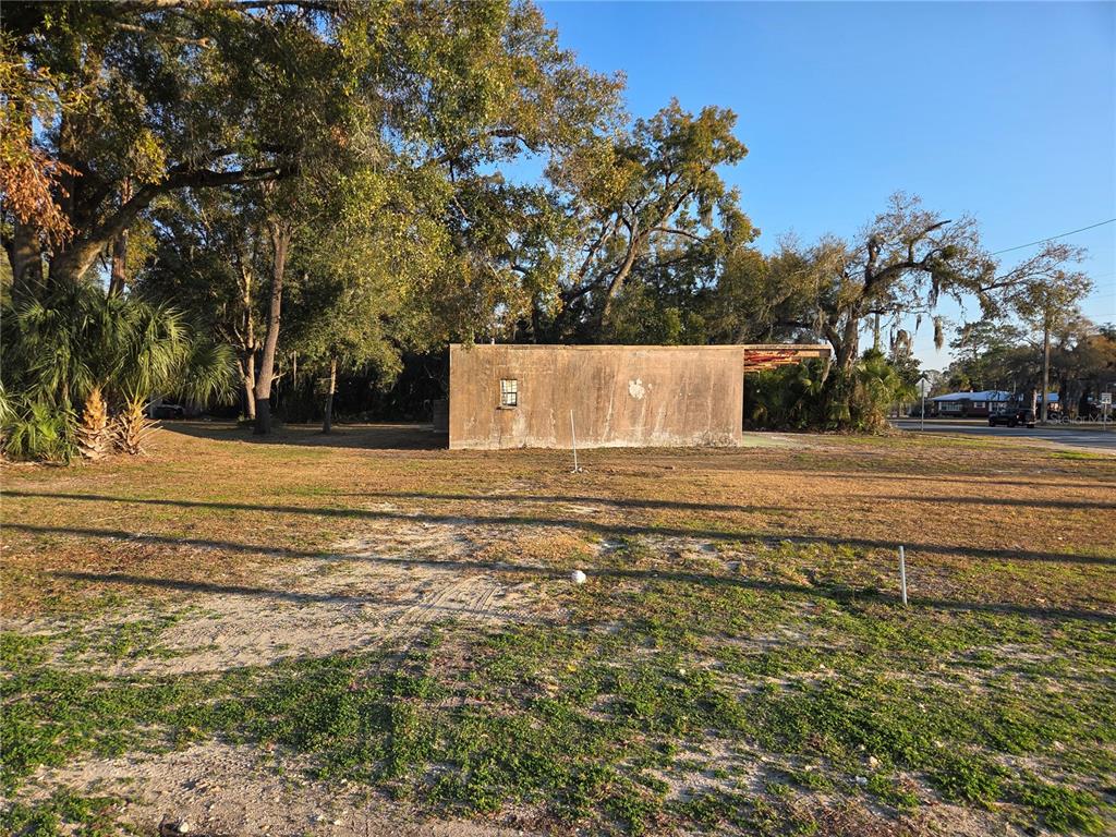 A weathered, rectangular concrete structure stands on a large, grassy lot with mature trees — 715 N YOUNG BOULEVARD, CHIEFLAND, FL