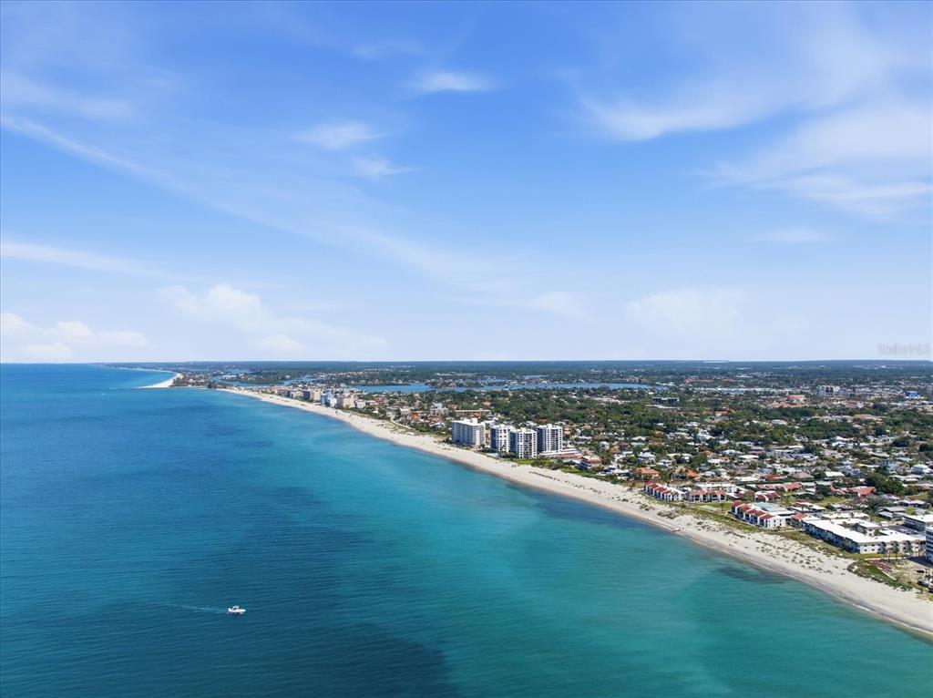An aerial view shows a sandy beach coastline with ocean water and nearby residential buildings — 500 PARK BOULEVARD S UNIT 106, VENICE, FL