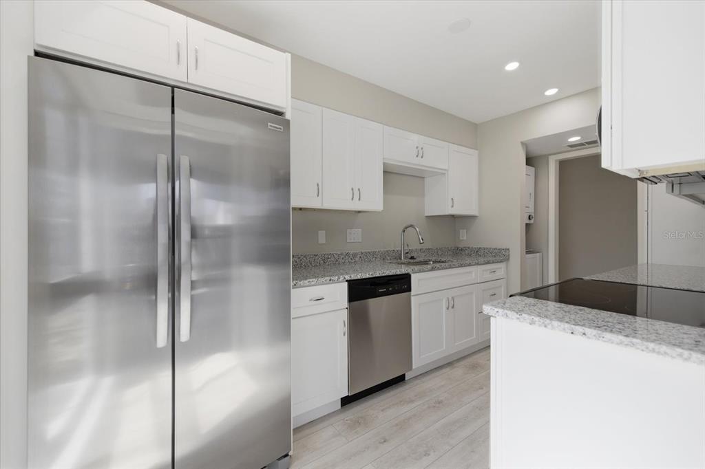 A kitchen features stainless steel appliances, white cabinets, and speckled granite countertops — 500 PARK BOULEVARD S UNIT 106, VENICE, FL