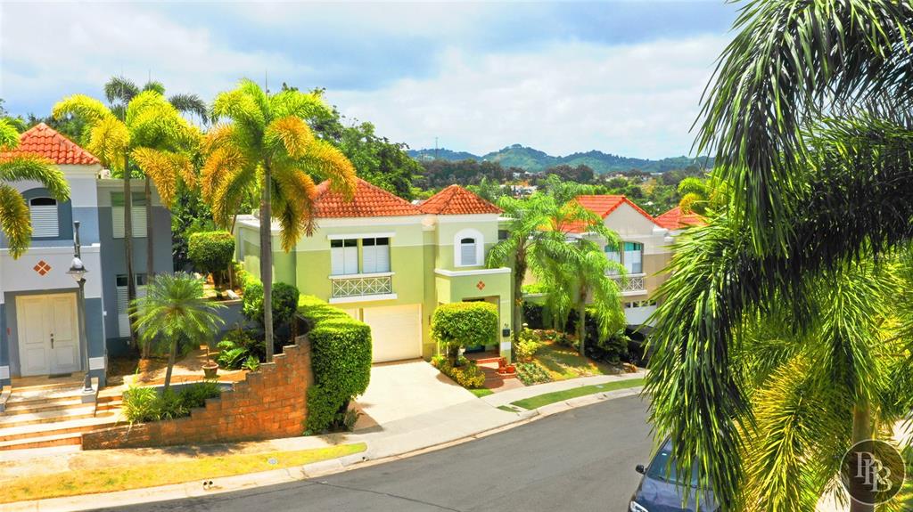 A street-level view of suburban houses with light green and grey facades and palm trees — 49 Vereda Street MONTEVERDE REAL DEV, SAN JUAN, PR