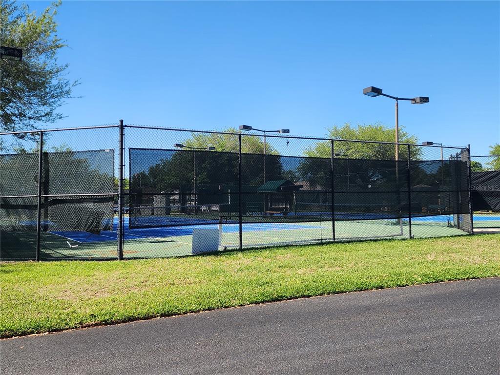 A fenced-in outdoor tennis court with blue and green surfaces under a clear sky — 1715 SW 157TH PLACE ROAD, OCALA, FL