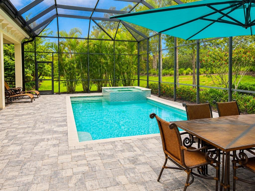 A screened-in patio features a rectangular swimming pool with an attached spa and dining furniture — 7908 MATERA COURT, BRADENTON, FL