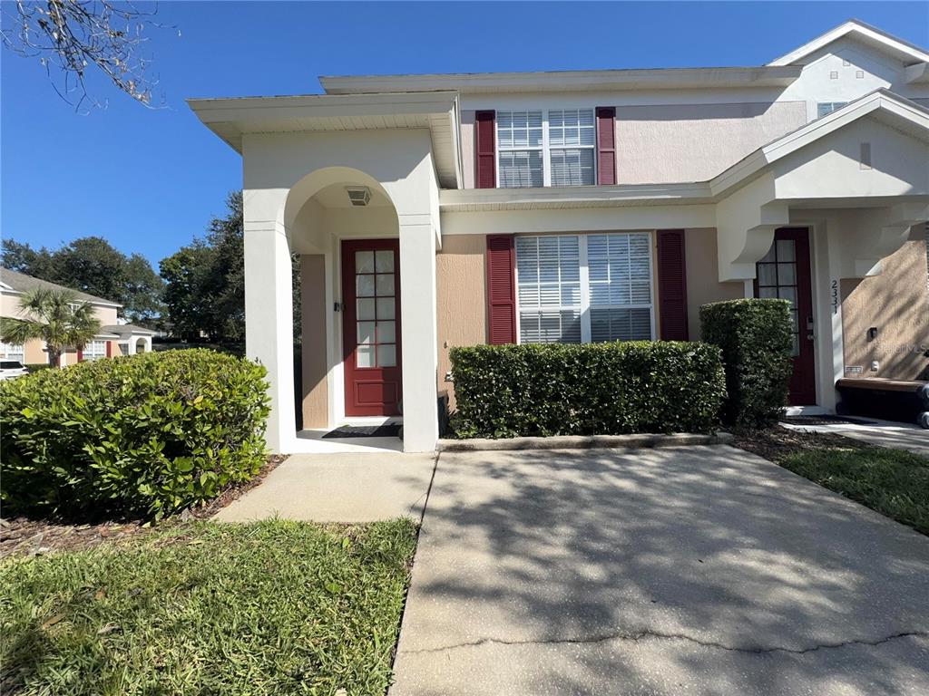 A tan townhouse exterior features a covered entryway, red front door, and red window shutters — 2333 SILVER PALM DRIVE, KISSIMMEE, FL