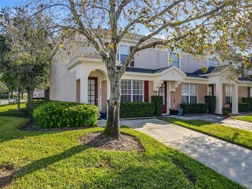 A two-story townhouse exterior features a beige facade, arched entryways, and a concrete driveway — 2333 SILVER PALM DRIVE, KISSIMMEE, FL