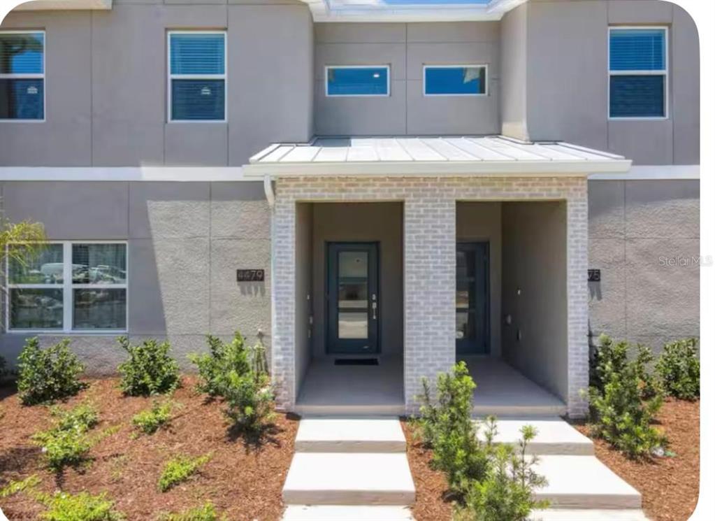 The exterior of a two-story townhouse features a covered entryway with light brick columns — 4479 SCENE LANE, KISSIMMEE, FL