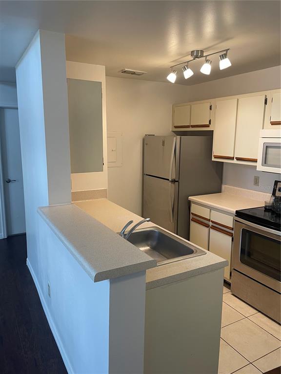 A kitchen features white cabinets, stainless steel appliances, a sink, and a breakfast bar — 5992 WESTGATE DRIVE UNIT 302, ORLANDO, FL