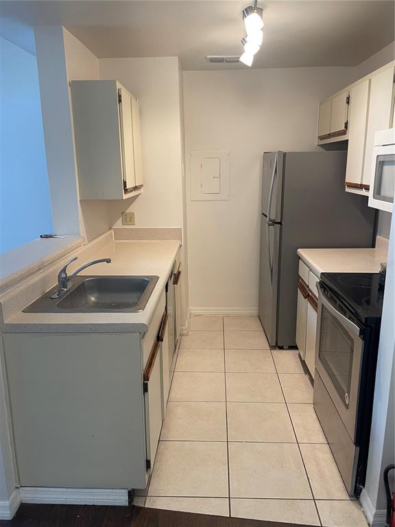 A galley kitchen features white cabinets, light countertops, a stainless steel sink, and tile flooring — 5992 WESTGATE DRIVE UNIT 302, ORLANDO, FL