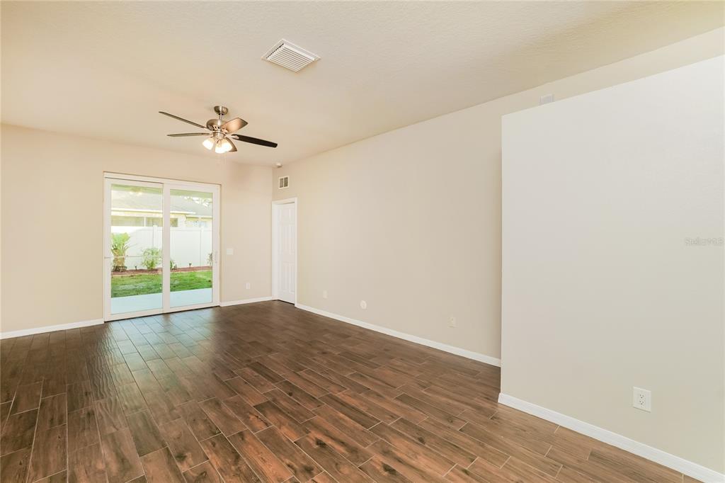 An empty room with wood-look tile flooring, a ceiling fan, and sliding glass patio doors — 3610 BENERAID STREET, LAND O LAKES, FL