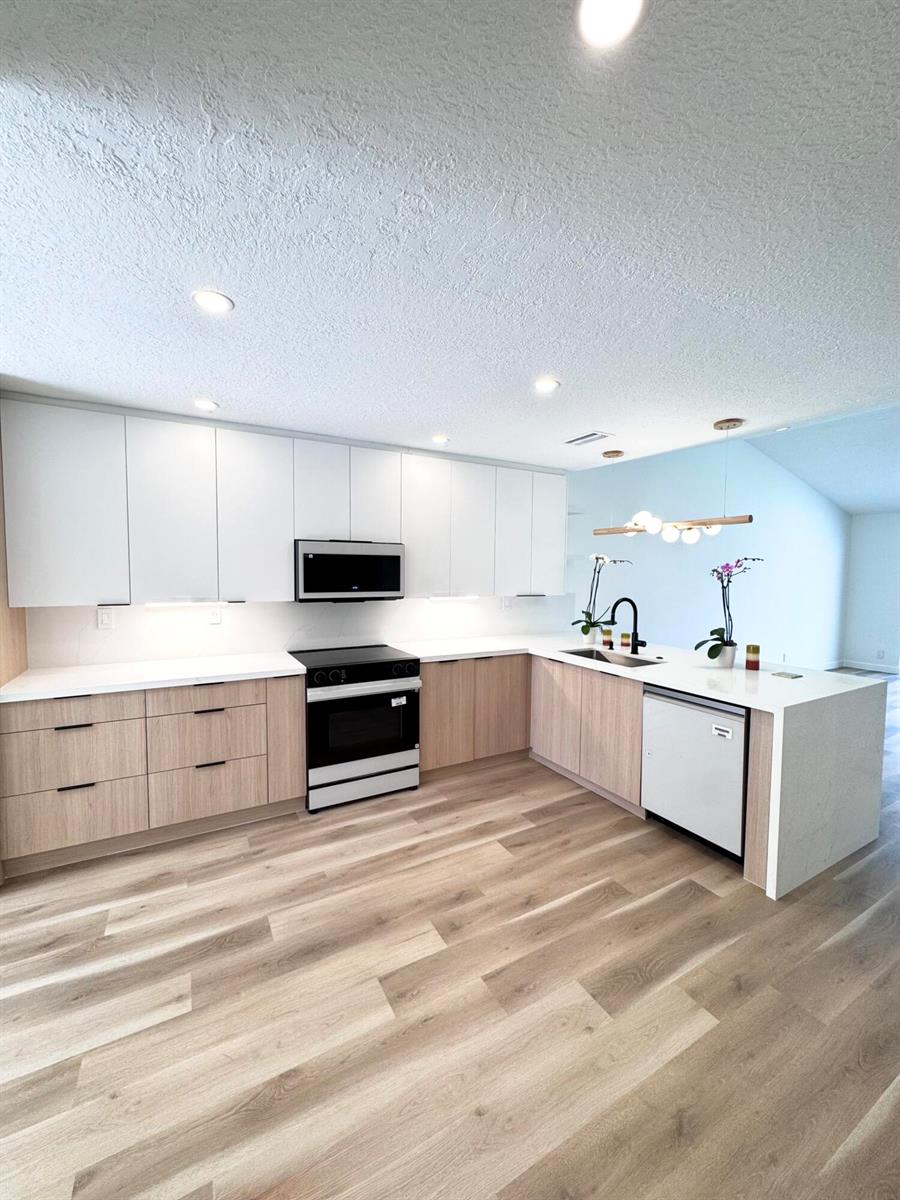 A modern kitchen features white upper cabinets, light wood lower cabinets, and a white countertop — 21547 Altamira Avenue, Boca Raton FL 33433, BOCA RATON, FL