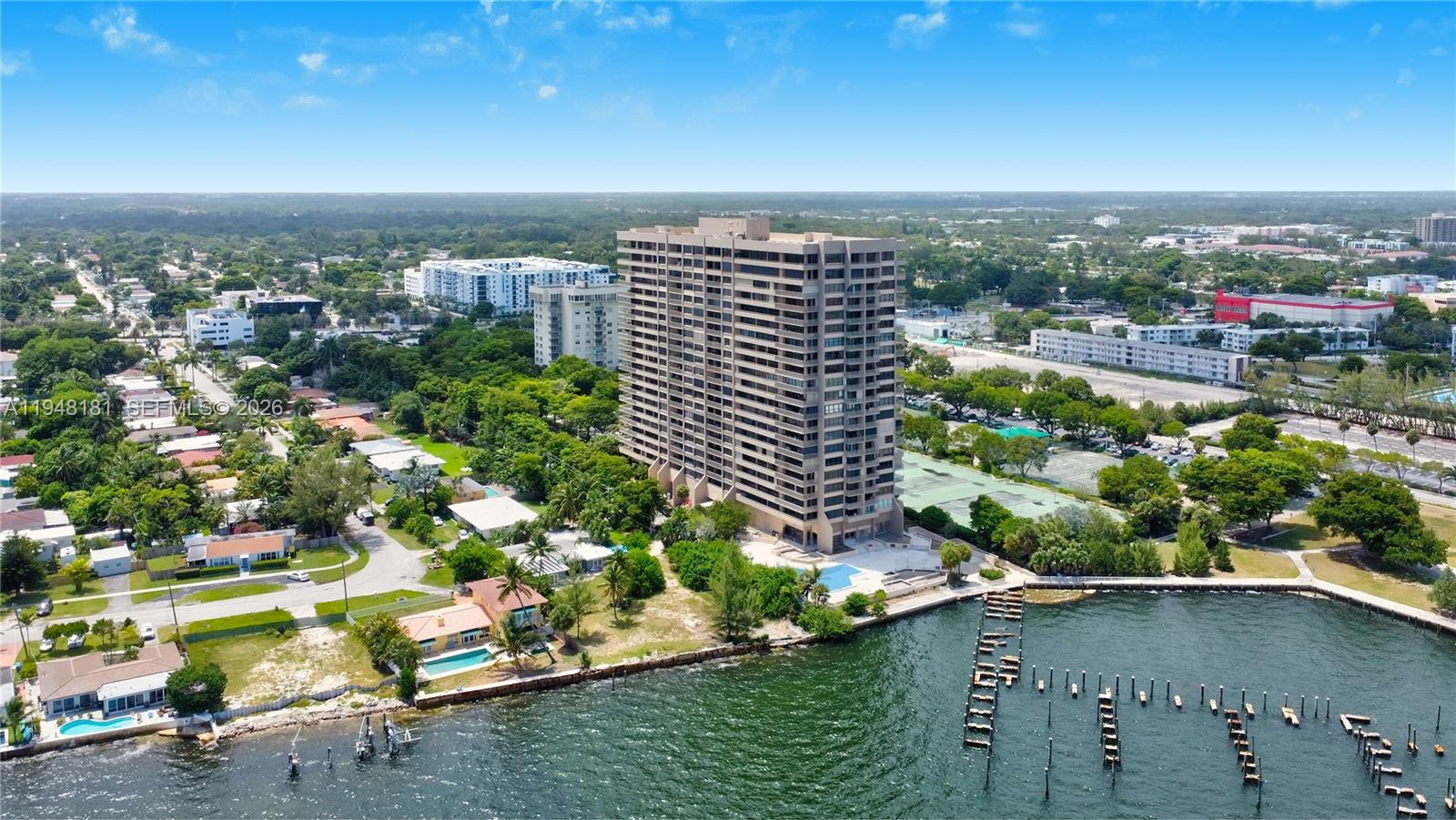 An aerial view shows a tall residential building situated on a waterfront lot — 11113 Biscayne Blvd, Miami FL 33181, MIAMI, FL