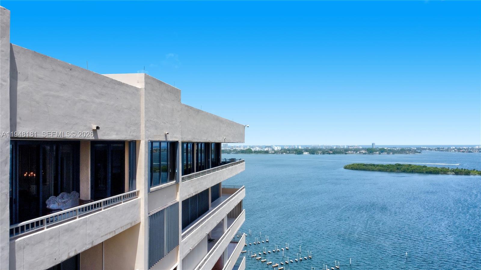 An exterior view of a multi-story building with balconies overlooking a large body of water — 11113 Biscayne Blvd, Miami FL 33181, MIAMI, FL