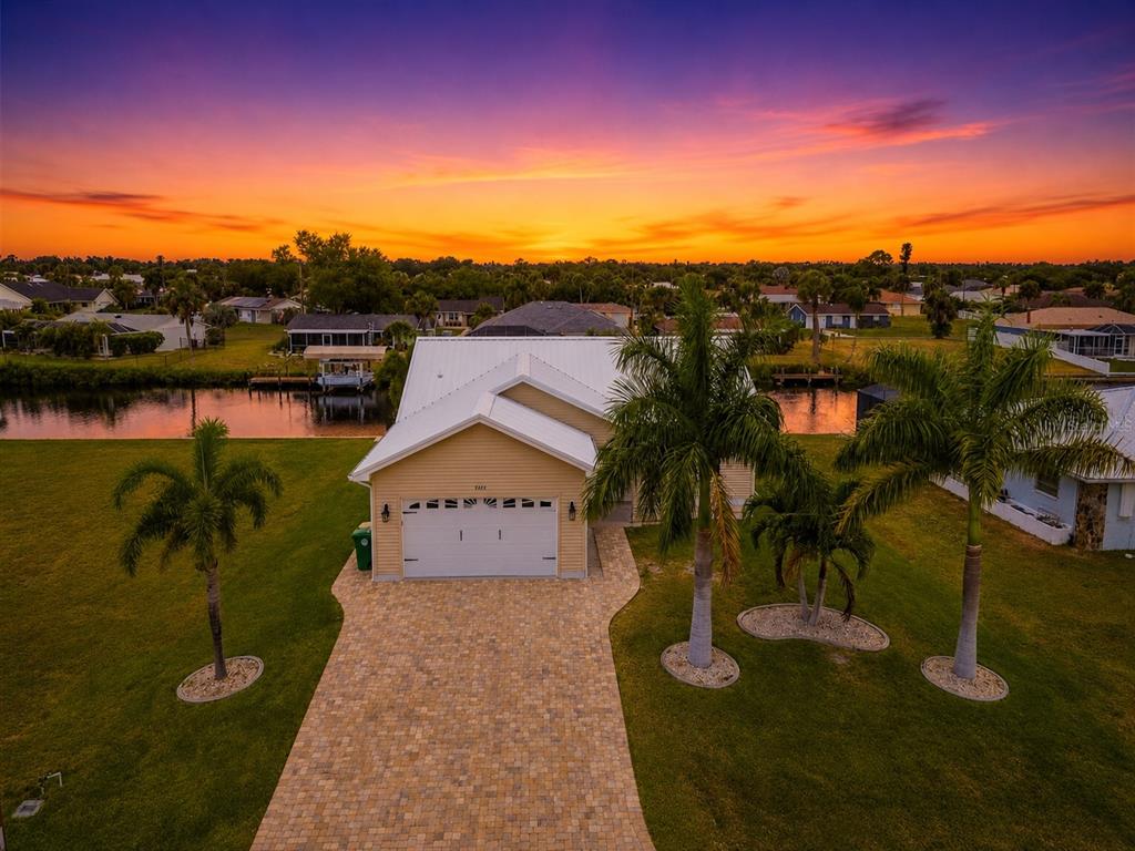 An aerial view of a tan house with a white roof, paver driveway, and palm trees — 4462 EWING CIRCLE, PORT CHARLOTTE, FL