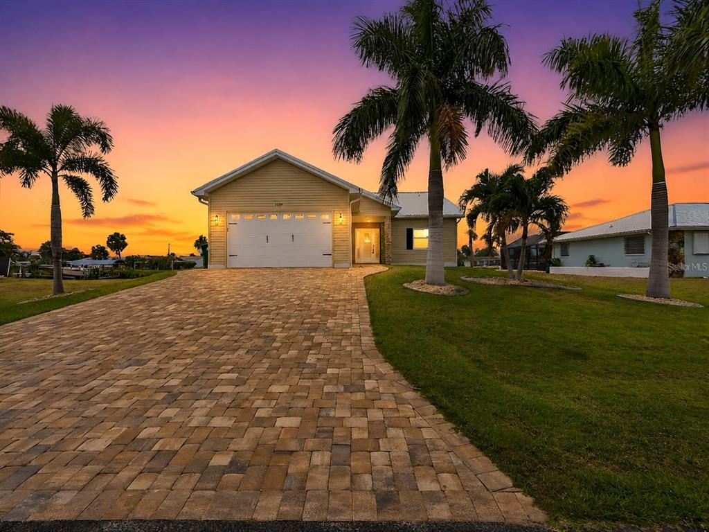 A single-story house with a paved driveway and palm trees under a sunset sky — 4462 EWING CIRCLE, PORT CHARLOTTE, FL