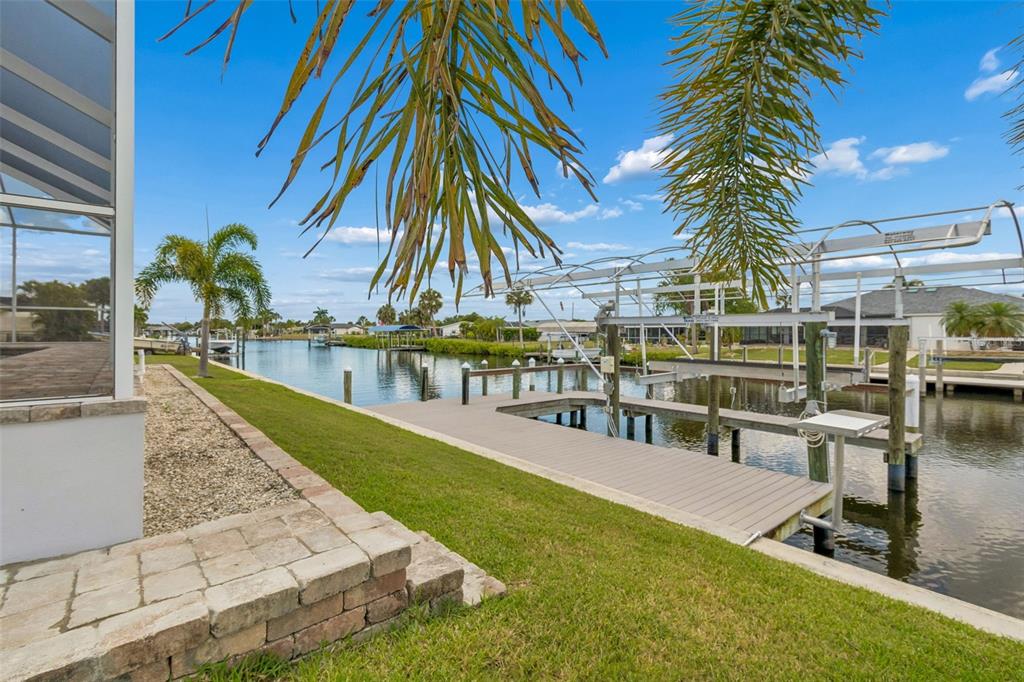 A backyard view featuring a wooden boat dock, a boat lift, and a canal — 4462 EWING CIRCLE, PORT CHARLOTTE, FL