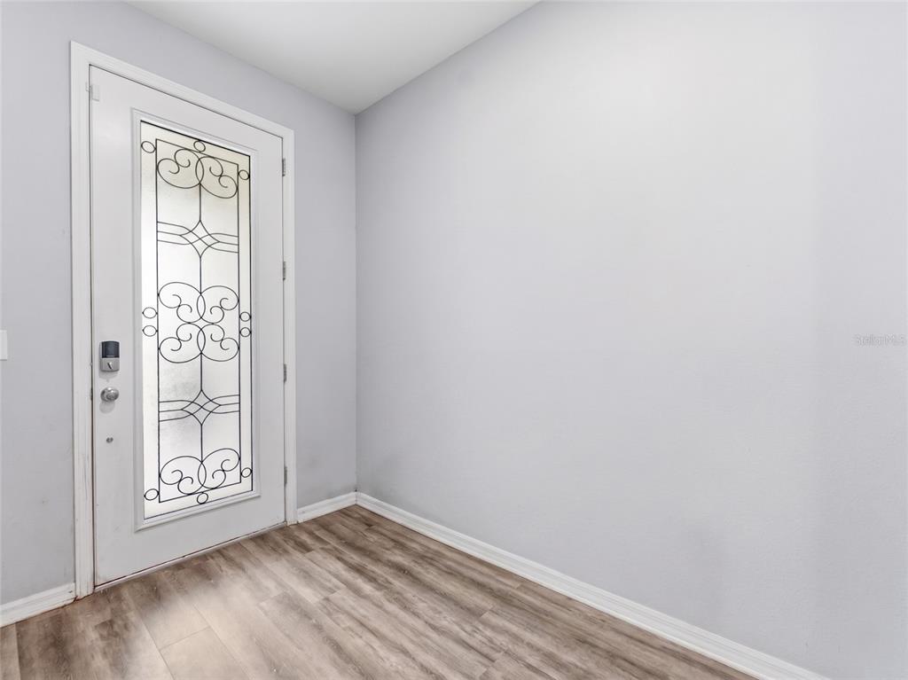An entryway features light gray walls, wood-look flooring, and a white door with decorative glass — 16357 TREASURE POINT DRIVE, WIMAUMA, FL