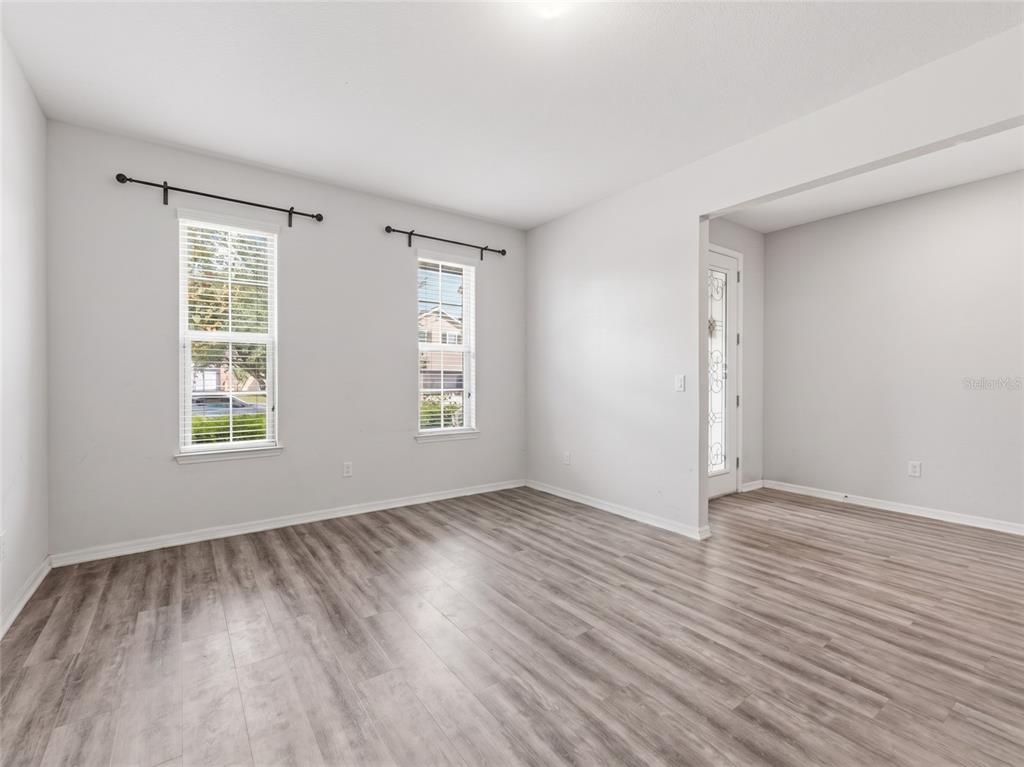 An empty room features light gray walls, wood-look flooring, and two windows with curtain rods — 16357 TREASURE POINT DRIVE, WIMAUMA, FL