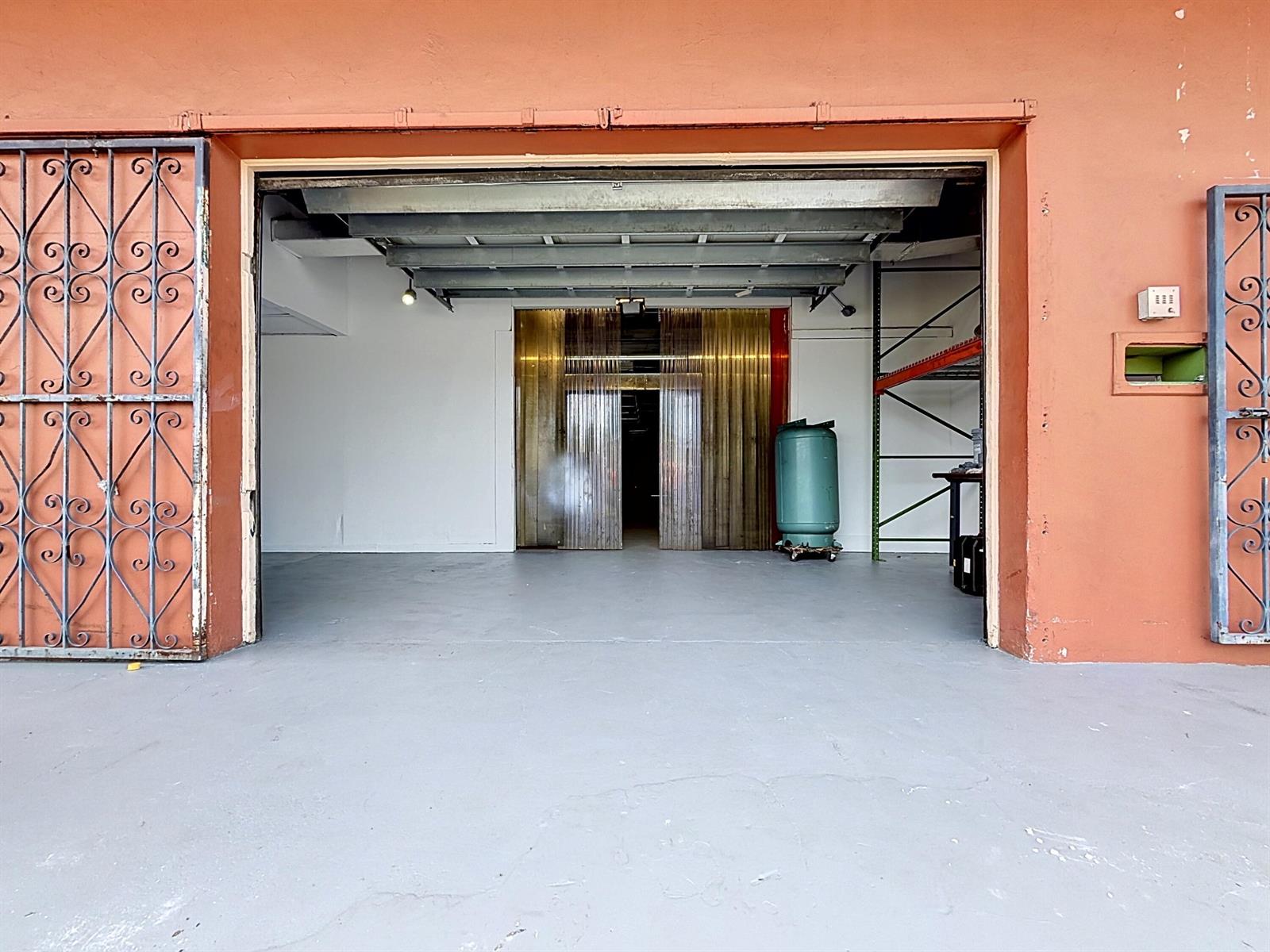 An open warehouse bay features a gray concrete floor, metal ceiling beams, and sliding gates — 3411 NE 6th Terrace, Pompano Beach FL 33064, POMPANO BEACH, FL