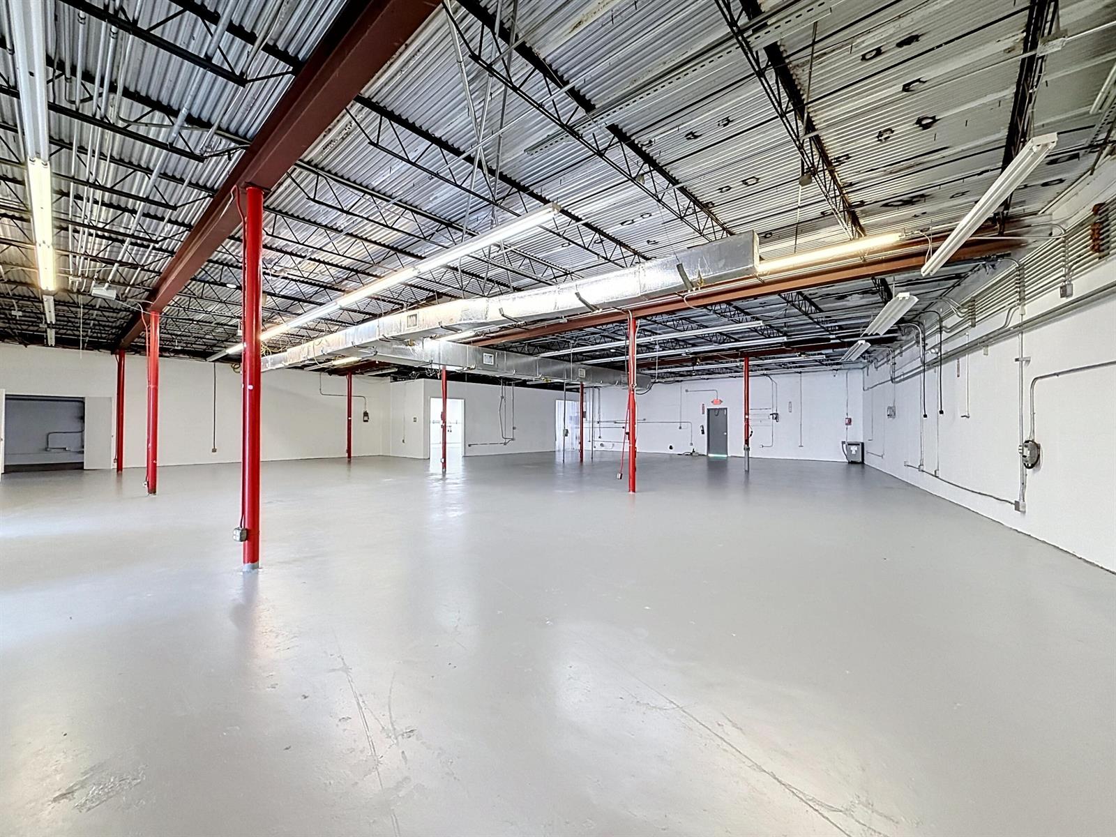 An empty industrial warehouse space features a gray concrete floor, white walls, and exposed ceilings — 3411 NE 6th Terrace, Pompano Beach FL 33064, POMPANO BEACH, FL