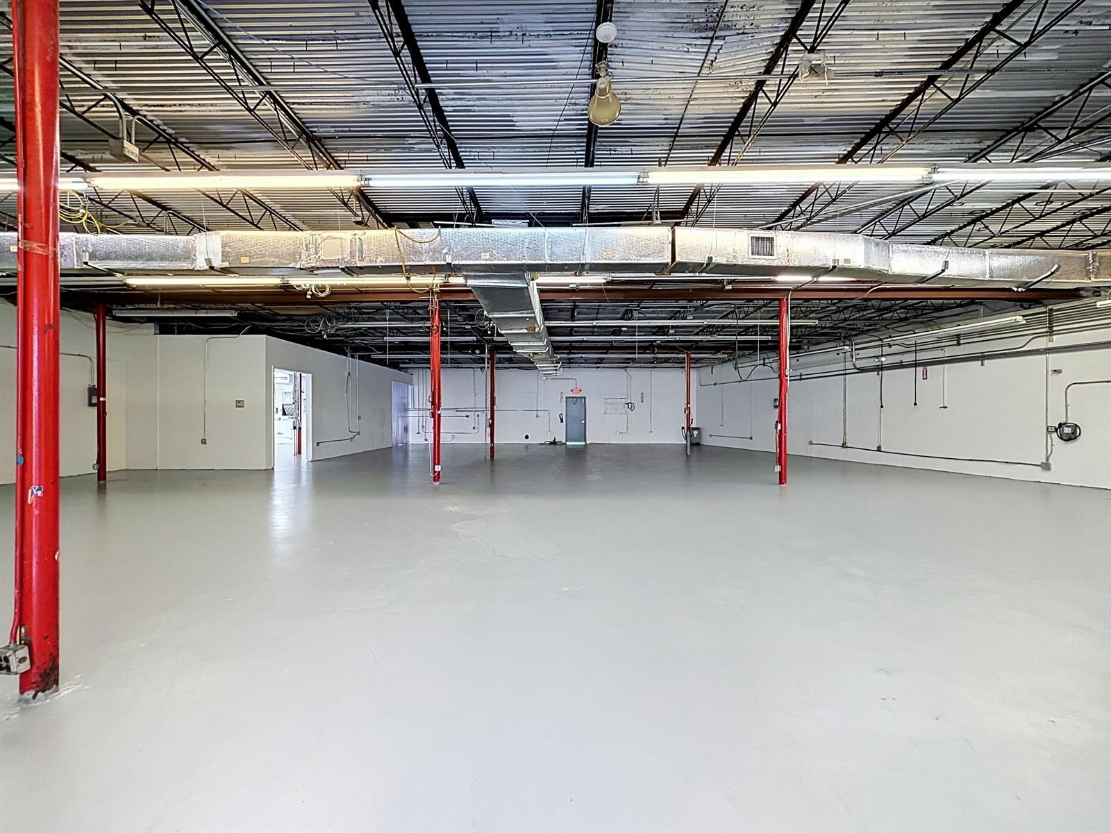 An empty industrial warehouse space features a gray concrete floor, red support columns, and ductwork — 3411 NE 6th Terrace, Pompano Beach FL 33064, POMPANO BEACH, FL