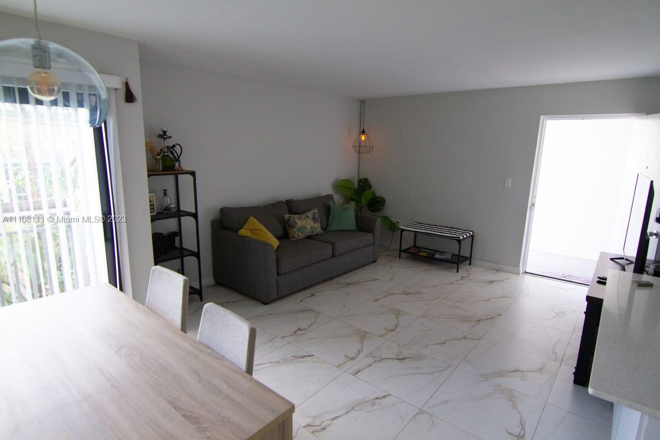A living room with a gray sofa, marble-look tile floors, and a dining area — 753 Michigan # 3A, Miami Beach FL 33139, MIAMI BEACH, FL