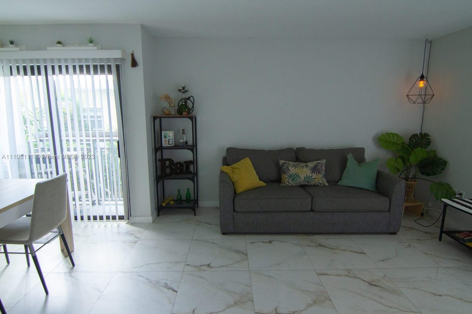 A living room features a gray sofa, a bar shelf, and white marble-look tile flooring — 753 Michigan # 3A, Miami Beach FL 33139, MIAMI BEACH, FL