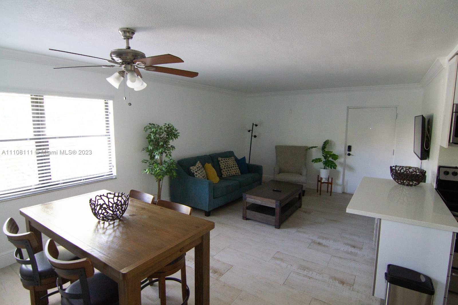 A living and dining area features a blue sofa, wooden table, and tile flooring — 753 Michigan # 3A, Miami Beach FL 33139, MIAMI BEACH, FL