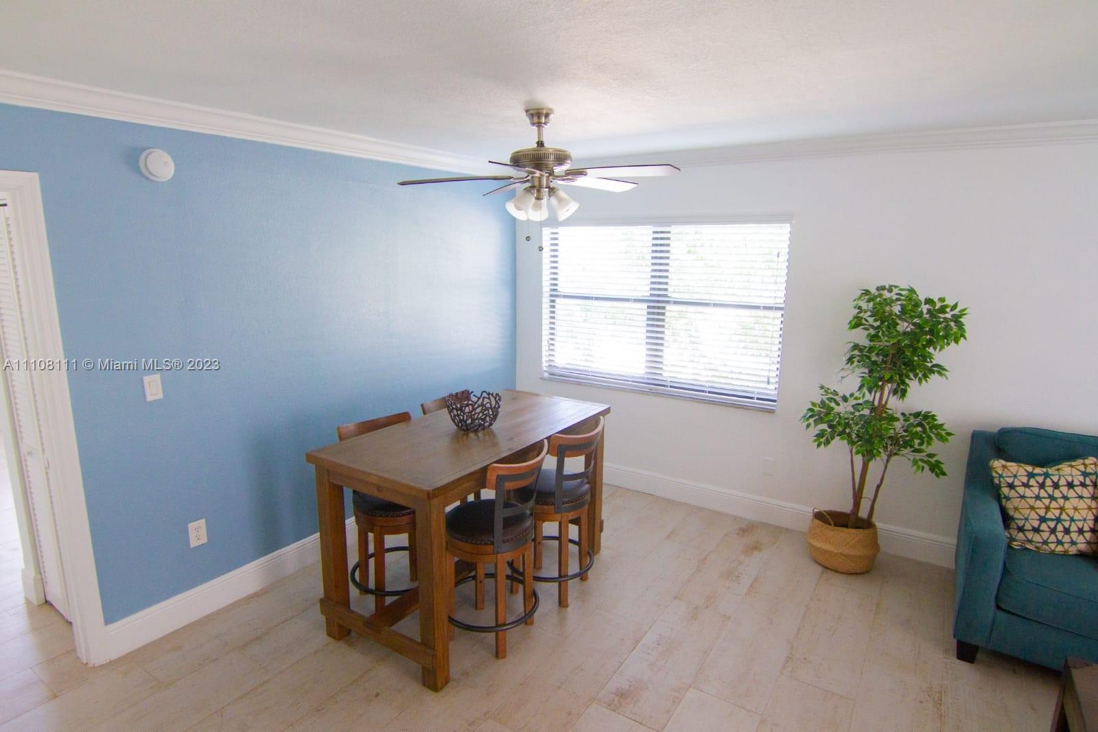 A dining area features a wooden table with four stools, a blue accent wall, and flooring — 753 Michigan # 3A, Miami Beach FL 33139, MIAMI BEACH, FL