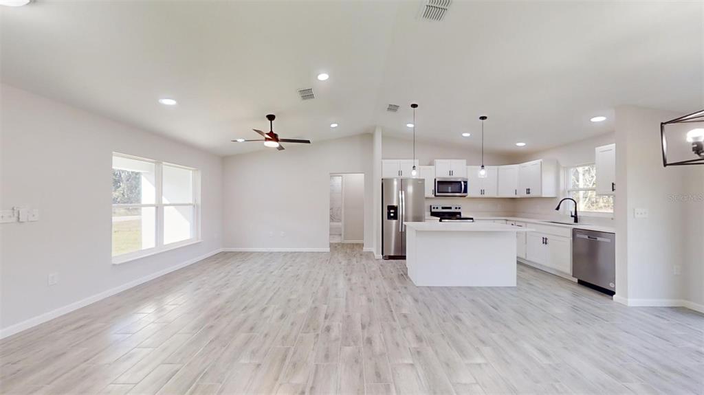 An open-concept kitchen and living area features white cabinetry, stainless steel appliances, and light flooring — 217 OAK LANE ROAD, OCALA, FL