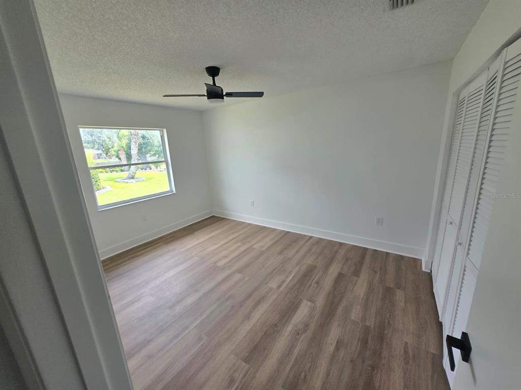 A bedroom with light wood-look flooring, white walls, a ceiling fan, and a louvered closet door — 3448 GLEN ABBEY LANE, LAKELAND, FL