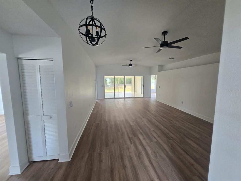 An open-concept living area features wood-look flooring, two ceiling fans, and a large sliding door — 3448 GLEN ABBEY LANE, LAKELAND, FL