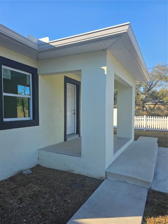 A light-colored house exterior features a covered front porch, a white door, and a window — 3704 SMITH TREE STREET, TAMPA, FL