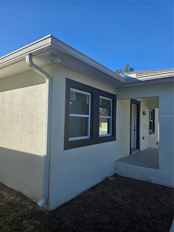 The exterior of a house features light-colored stucco walls, dark window trim, and a porch — 3704 SMITH TREE STREET, TAMPA, FL