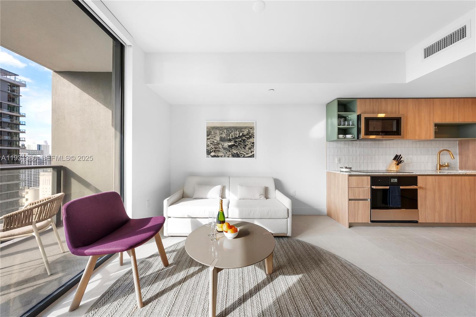 A modern studio apartment features a kitchenette, a white sofa, and a balcony with city views — 159 NE 6th St # 2608, Miami FL 33132, MIAMI, FL