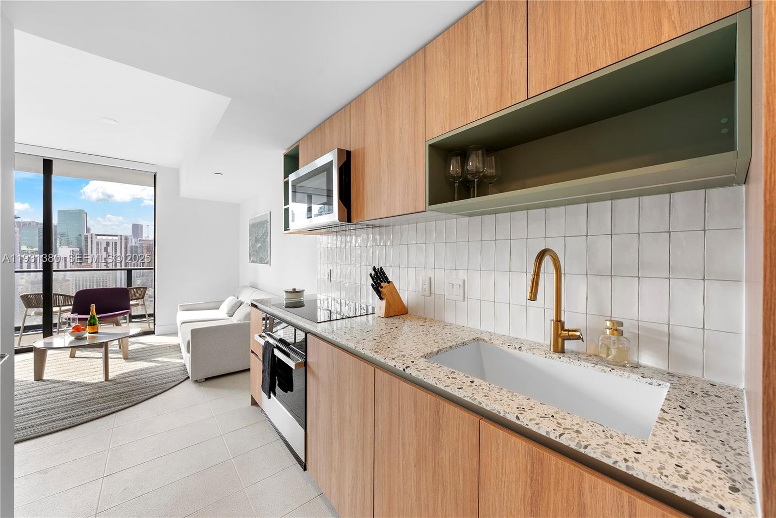 A modern kitchen features wood cabinets, a white tiled backsplash, and a terrazzo countertop — 159 NE 6th St # 2608, Miami FL 33132, MIAMI, FL