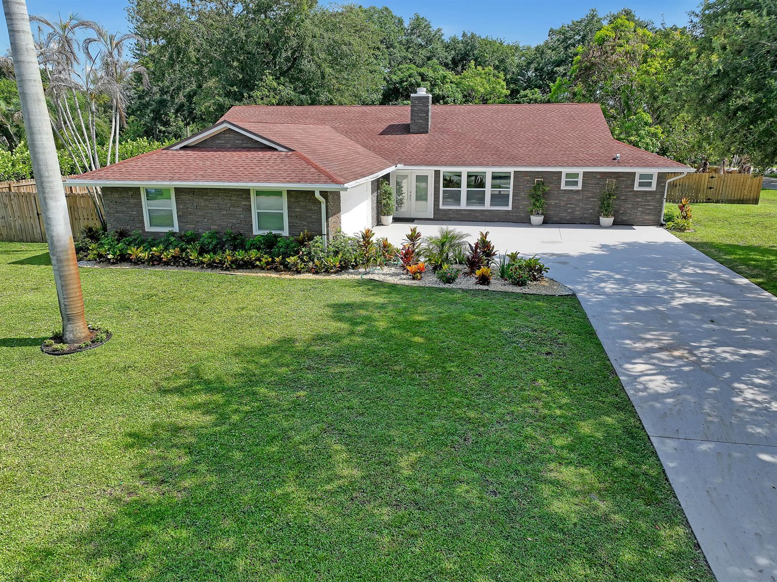 A single-story house with a stone facade, red roof, and a large concrete driveway — 6185 White Oak Court, Jupiter FL 33458, JUPITER, FL