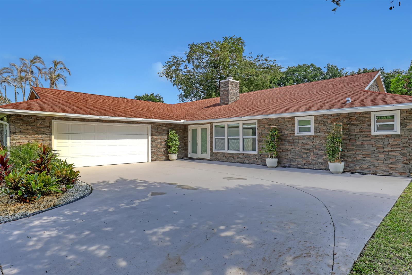 A single-story house with a stone facade, red roof, and a large concrete driveway — 6185 White Oak Court, Jupiter FL 33458, JUPITER, FL