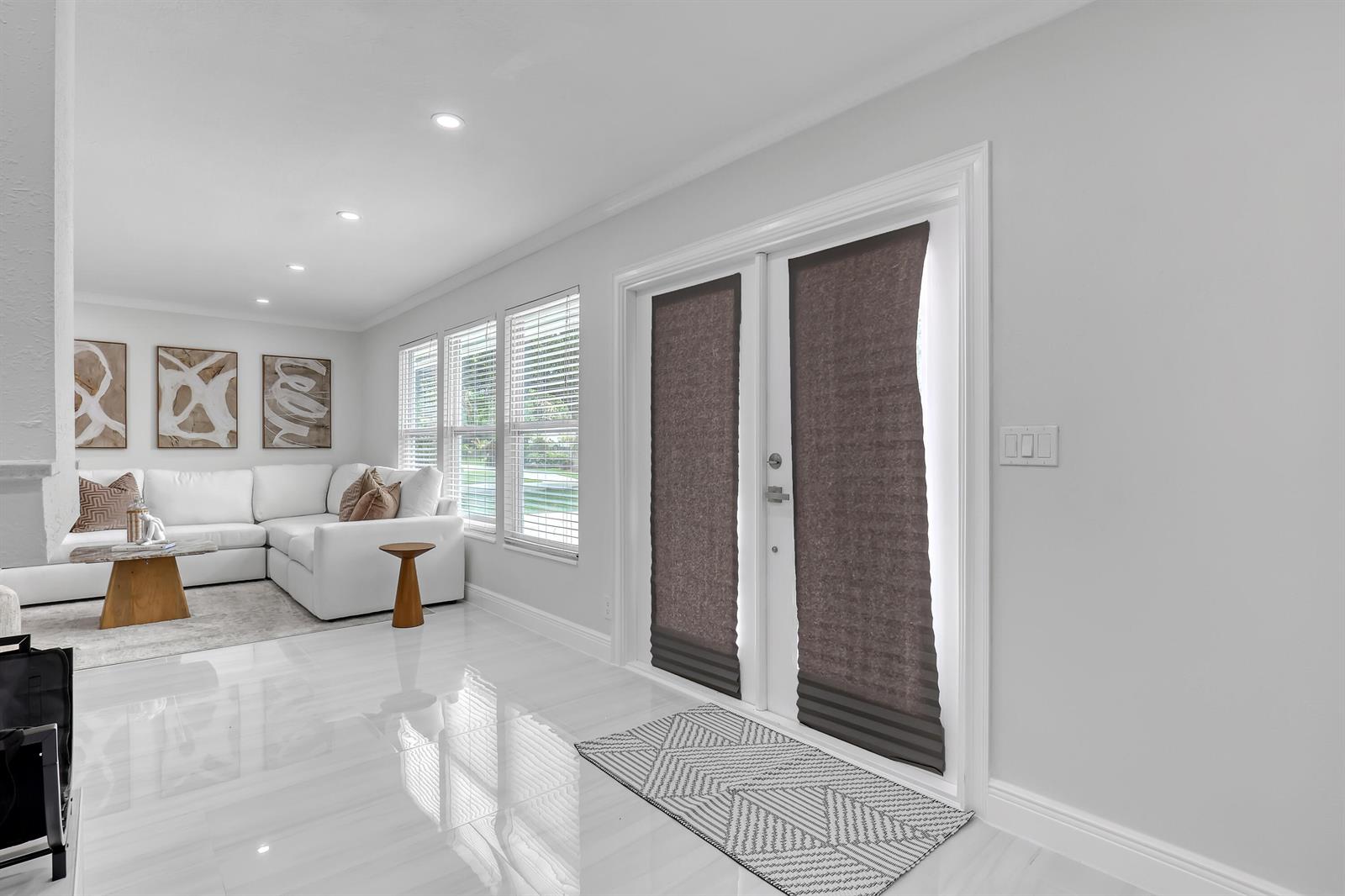 A bright living room with white tile floors, a sectional sofa, and double glass doors — 6185 White Oak Court, Jupiter FL 33458, JUPITER, FL