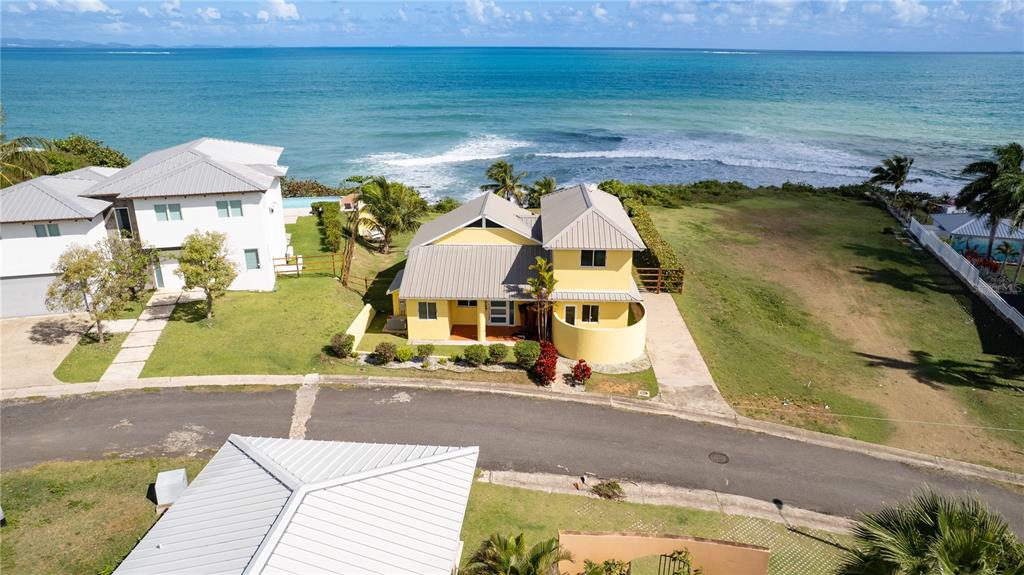 An aerial view shows a yellow house with a metal roof near the ocean — 5 BEACH VILLAGE, VIEQUES, PR