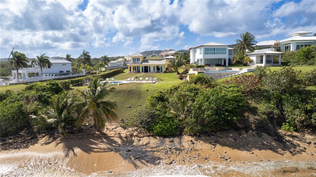 An aerial view shows several coastal houses with swimming pools situated above a sandy beach — 5 BEACH VILLAGE, VIEQUES, PR