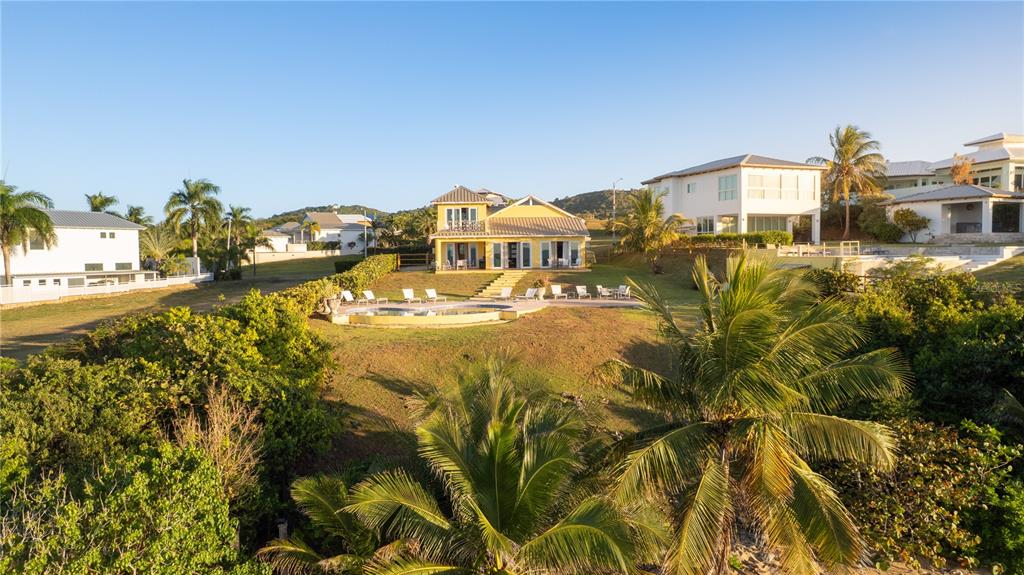 An exterior view of a yellow house with a pool and palm trees — 5 BEACH VILLAGE, VIEQUES, PR