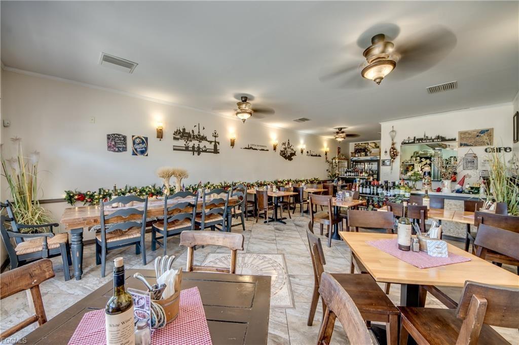 A restaurant dining room features wooden tables, chairs, tile flooring, and wall-mounted city skyline silhouettes — 2414 TAMIAMI TRAIL UNIT C, PORT CHARLOTTE, FL