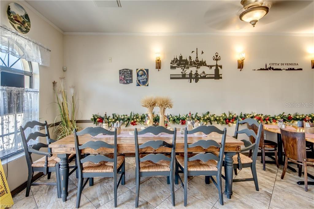 A dining room features a long wooden table with six chairs and wall-mounted city silhouettes — 2414 TAMIAMI TRAIL UNIT C, PORT CHARLOTTE, FL
