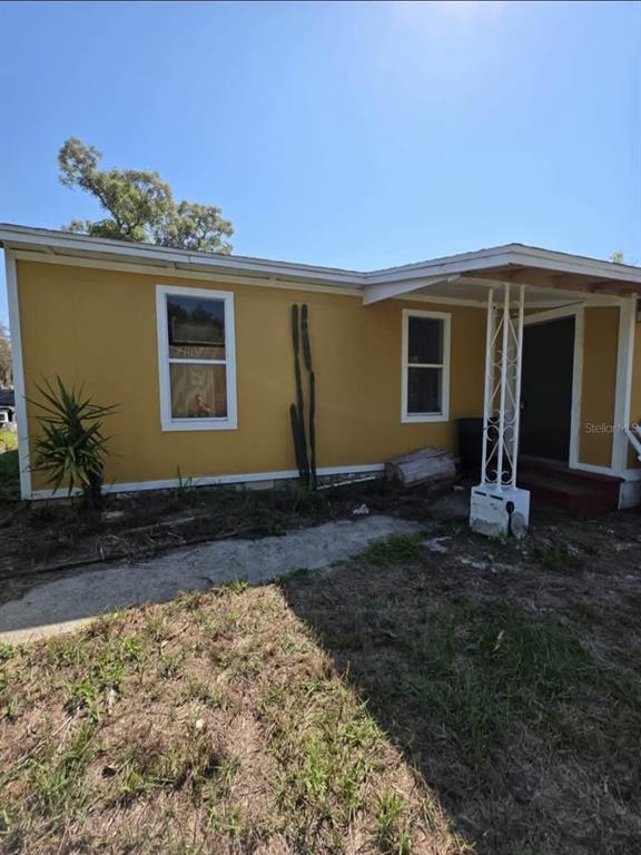 The exterior of a yellow house features a front porch with white metal supports — 33620 VERDA AVENUE, LEESBURG, FL