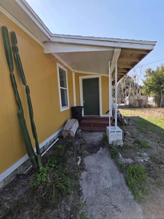 The exterior of a yellow house features a covered porch, a green door, and cacti — 33620 VERDA AVENUE, LEESBURG, FL