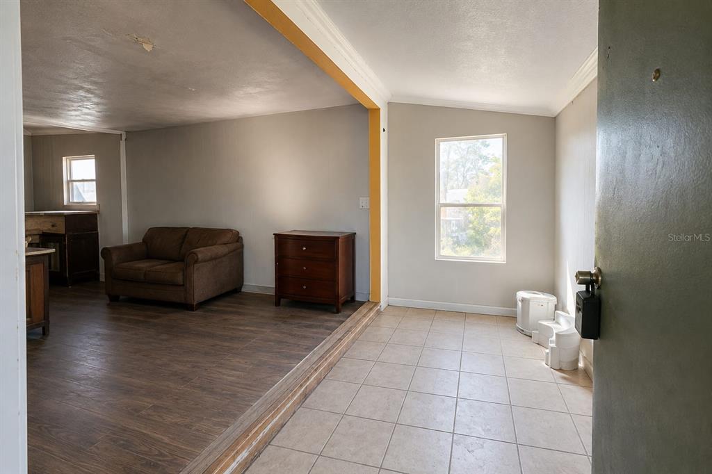 A living area with wood-look flooring transitions into a tiled entryway with a window — 33620 VERDA AVENUE, LEESBURG, FL